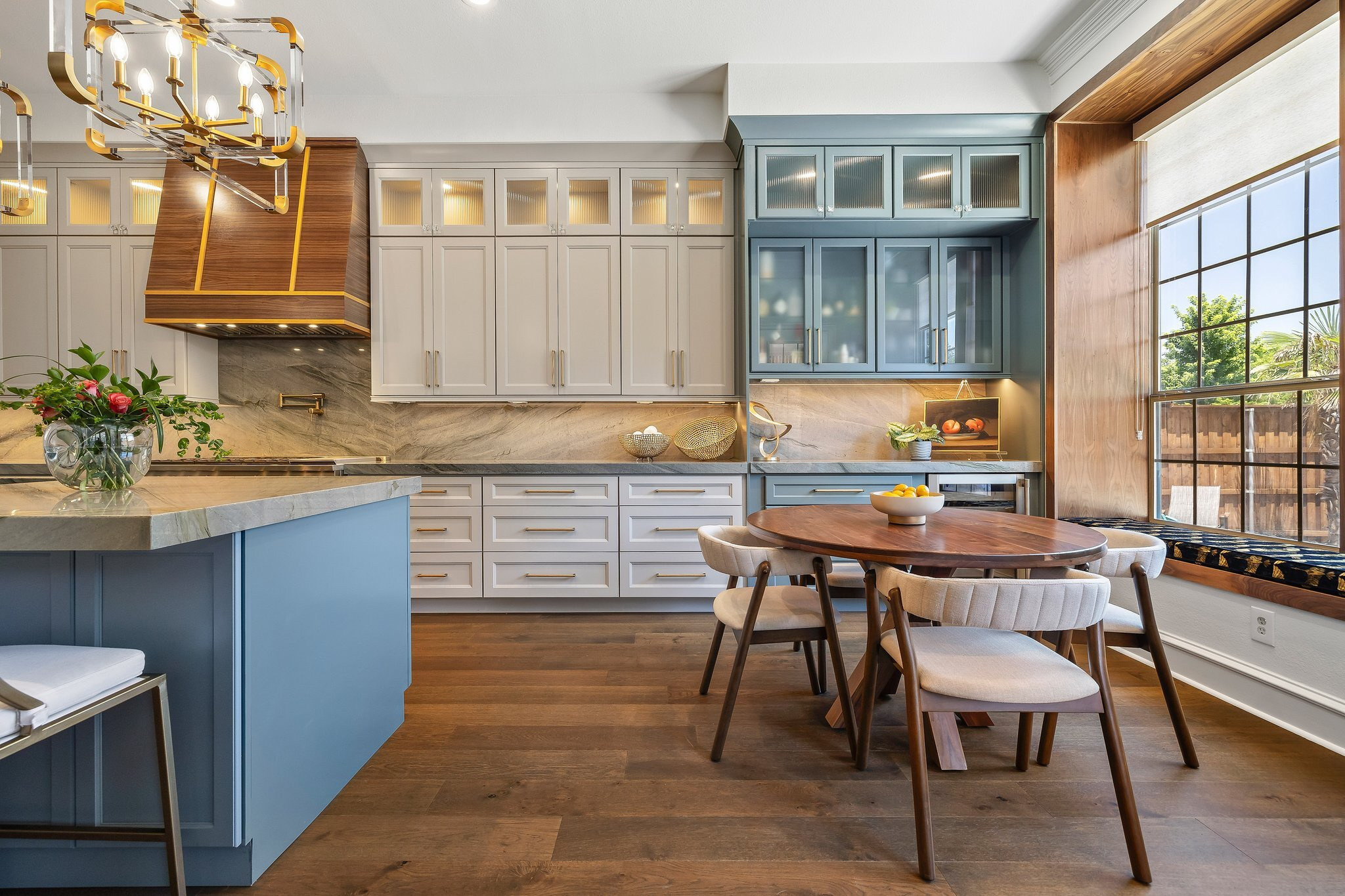 Kitchen with greige cabinetry, a blue island and a walnut range hood